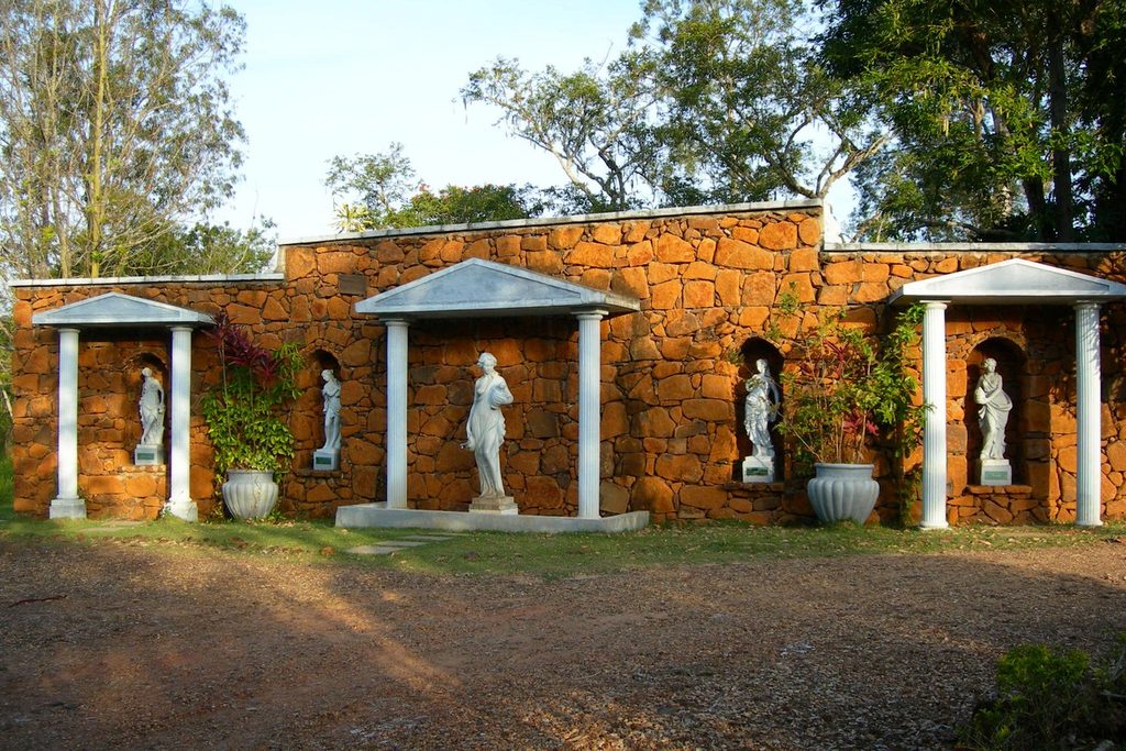 Muro de pedra com nichos, colunas brancas e estátuas clássicas na Fonte Almeida Salles