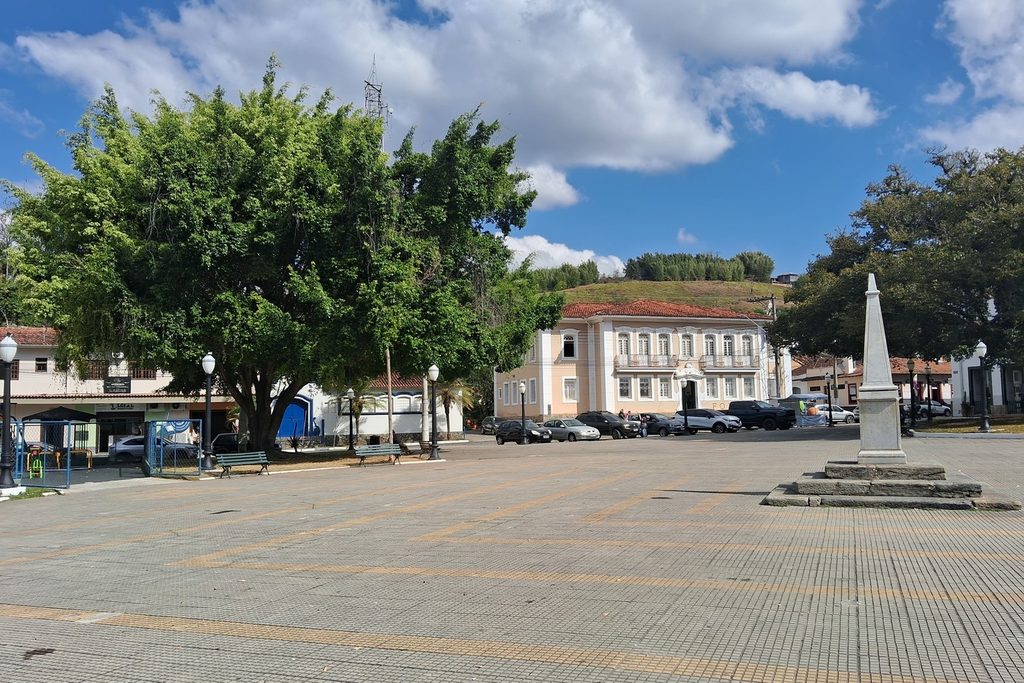 Praça ampla do centro histórico de Bananal, com árvore grande, marco de pedra e casarões ao fundo sob céu azul