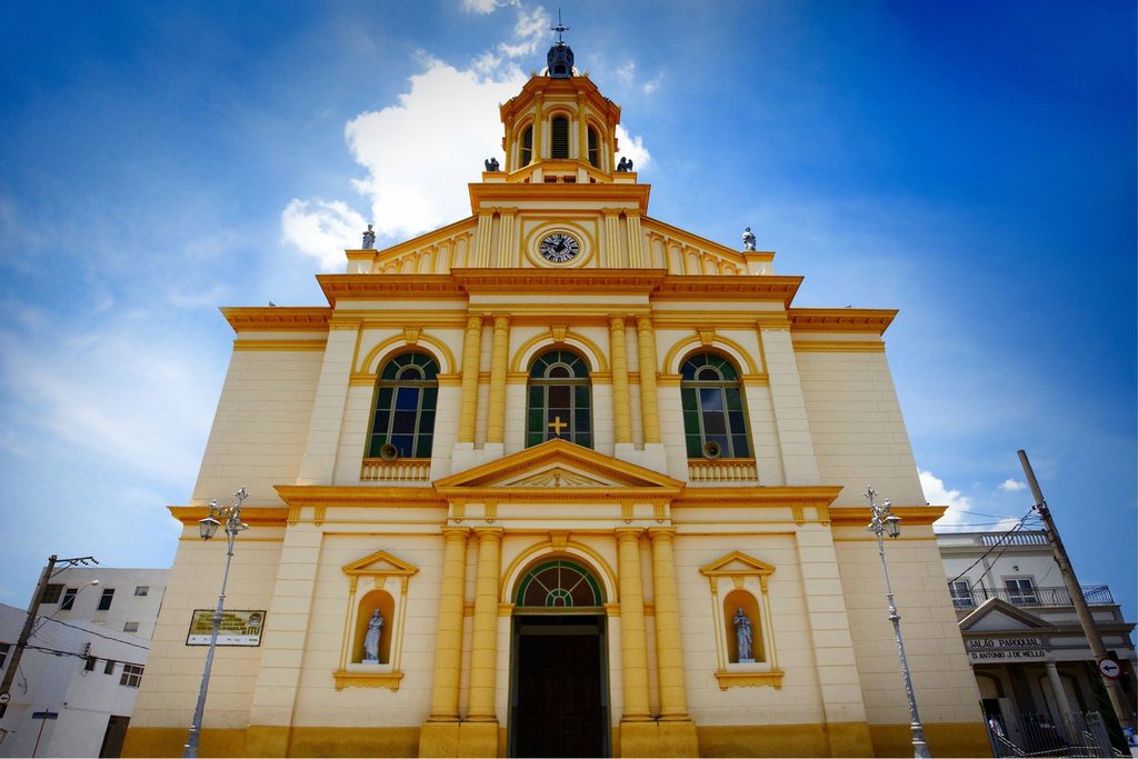 Fachada amarela e creme da Igreja Matriz de Nossa Senhora da Candelária, em Itu, com torre de relógio sob céu azul