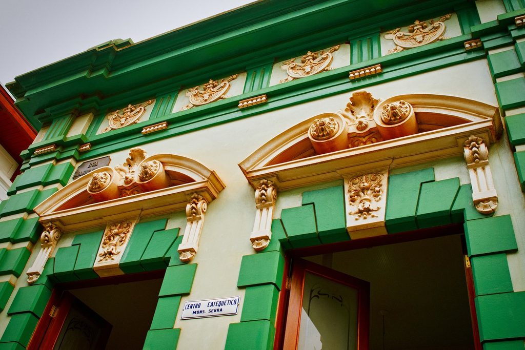 Fachada eclética verde e creme com relevos decorados sobre portas em arco, no centro histórico de Jaú