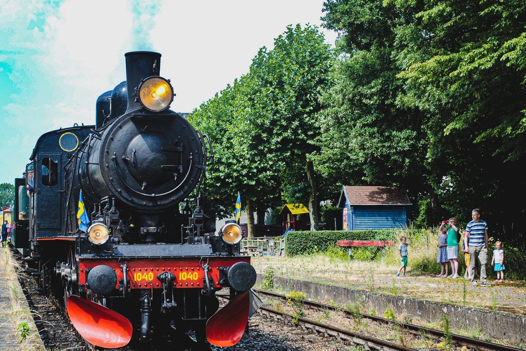 Locomotiva a vapor antiga parada em plataforma de estação ferroviária histórica de estilo europeu