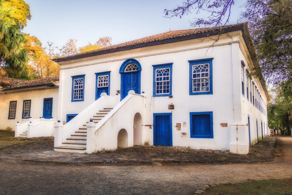 Casarão branco de dois andares com janelas e portas azuis e escadaria dupla, sede da antiga Fazenda Mato Dentro, em Campinas