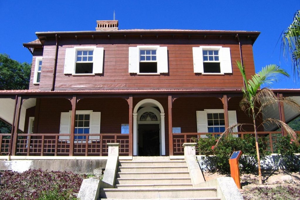 Casarão de madeira marrom de dois andares com janelas brancas e varanda, no alto de uma escadaria, o Museu Castelo de Paranapiacaba