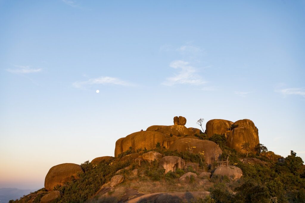 Grandes blocos de granito no topo da Pedra Grande, em Atibaia, ao entardecer, com a lua no céu