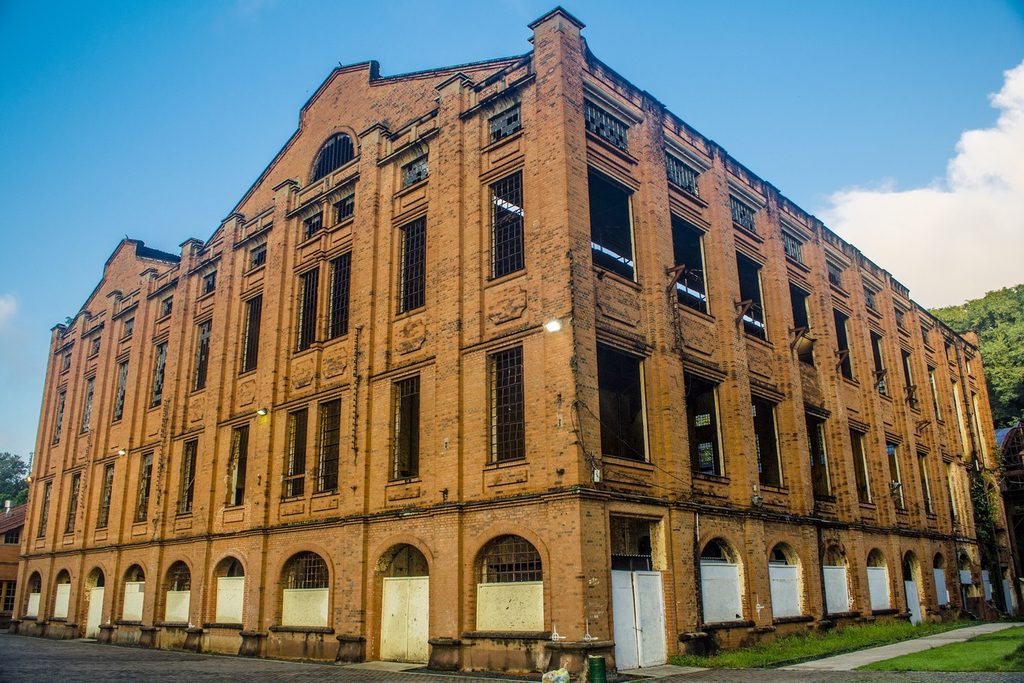 Prédio alto de tijolos aparentes com muitas janelas em arco, um dos armazéns do Engenho Central de Piracicaba