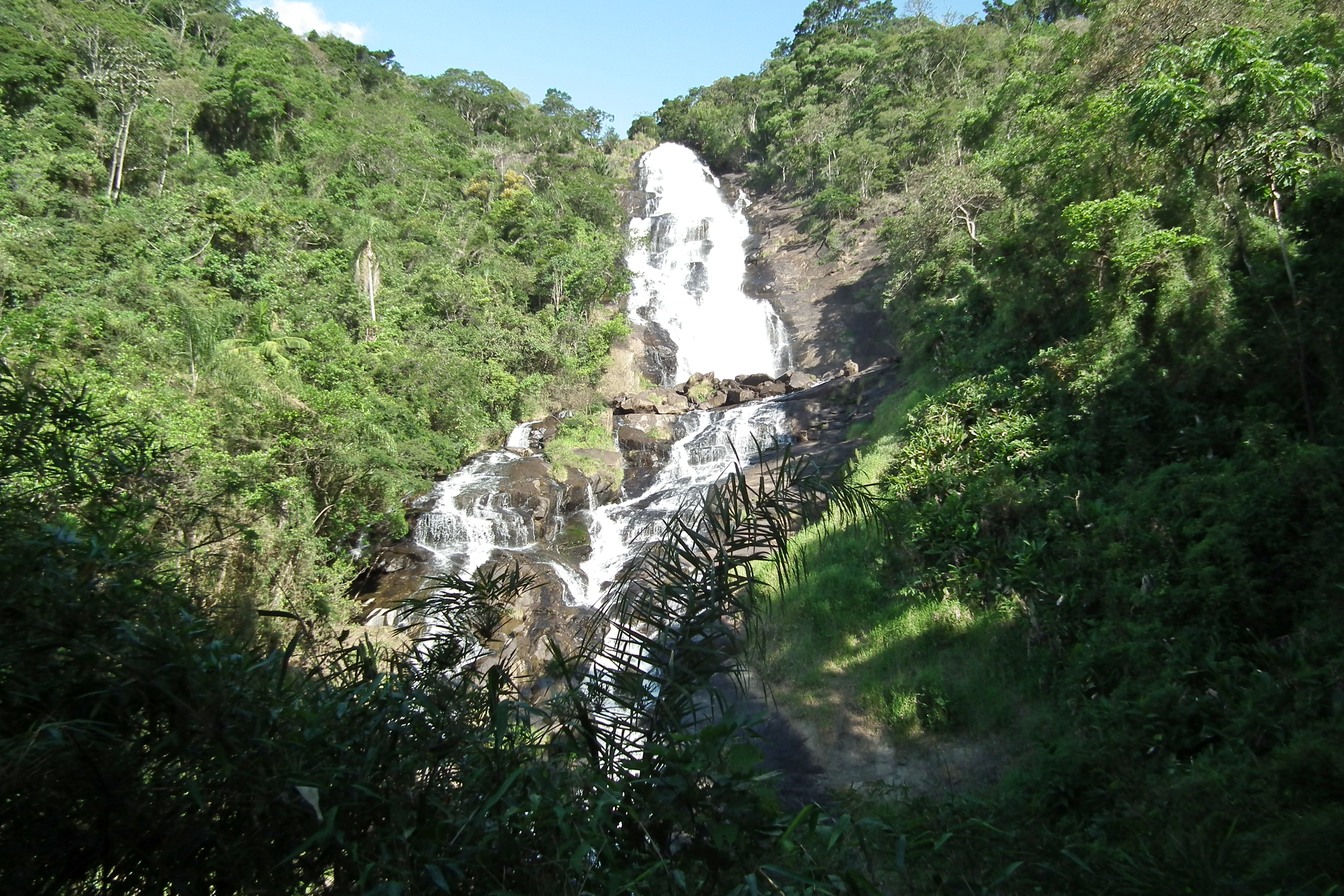 Cachoeira dos Pretos descendo em várias quedas brancas por um paredão de pedra no meio da mata verde