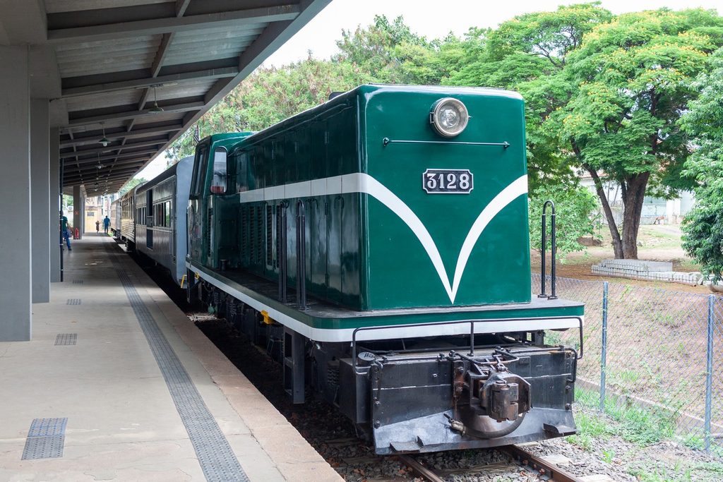 Locomotiva diesel verde e branca com o número 3128 parada na plataforma da estação de Salto, com vagões atrás e árvores ao fundo