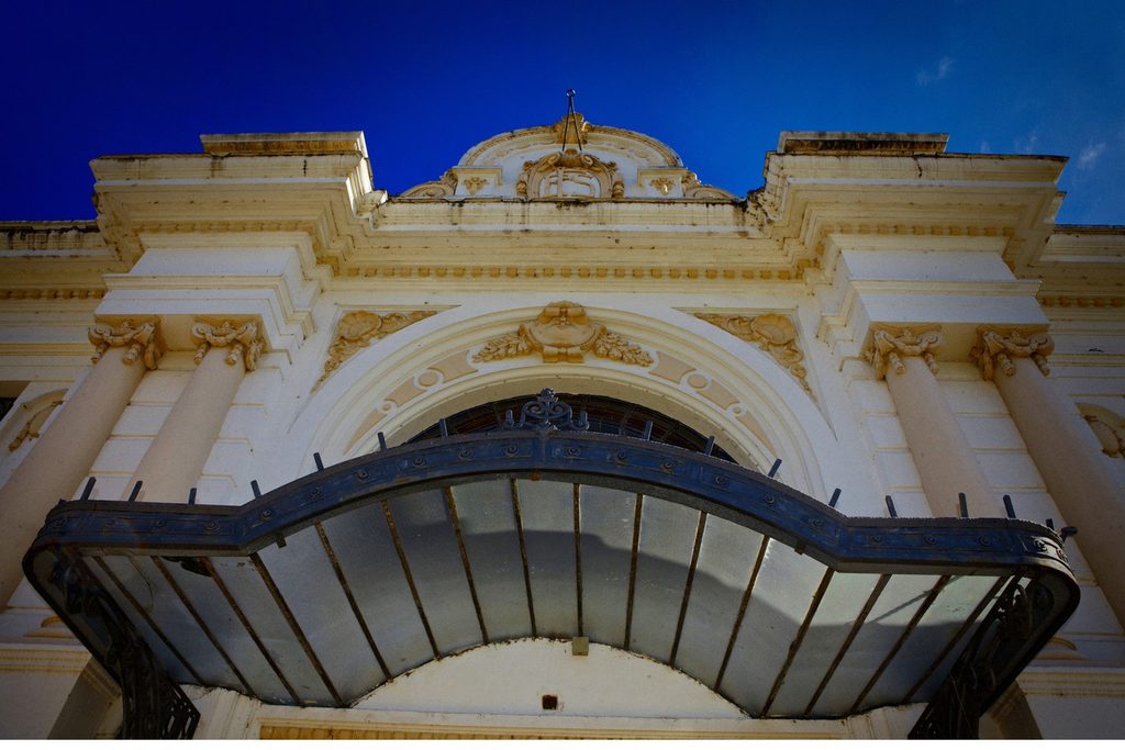 Fachada eclética branca da antiga Estação Ferroviária de Sorocaba, com colunas, ornamentos e marquise de ferro sob céu azul