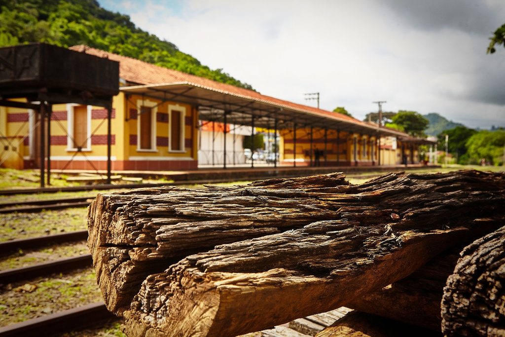 Prédio amarelo da antiga estação ferroviária de Águas da Prata, com plataforma coberta, trilhos e dormentes de madeira em primeiro plano