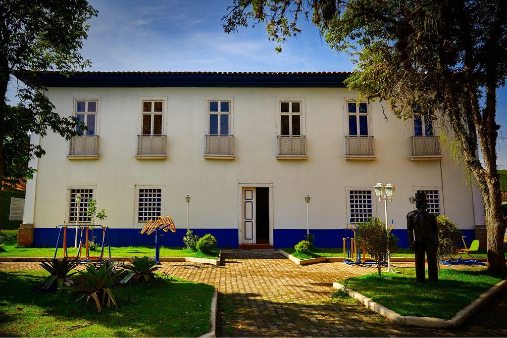 Prédio branco de dois andares da Casa da Cultura de Areias, antigo fórum onde Monteiro Lobato trabalhou, com jardim e estátua na frente