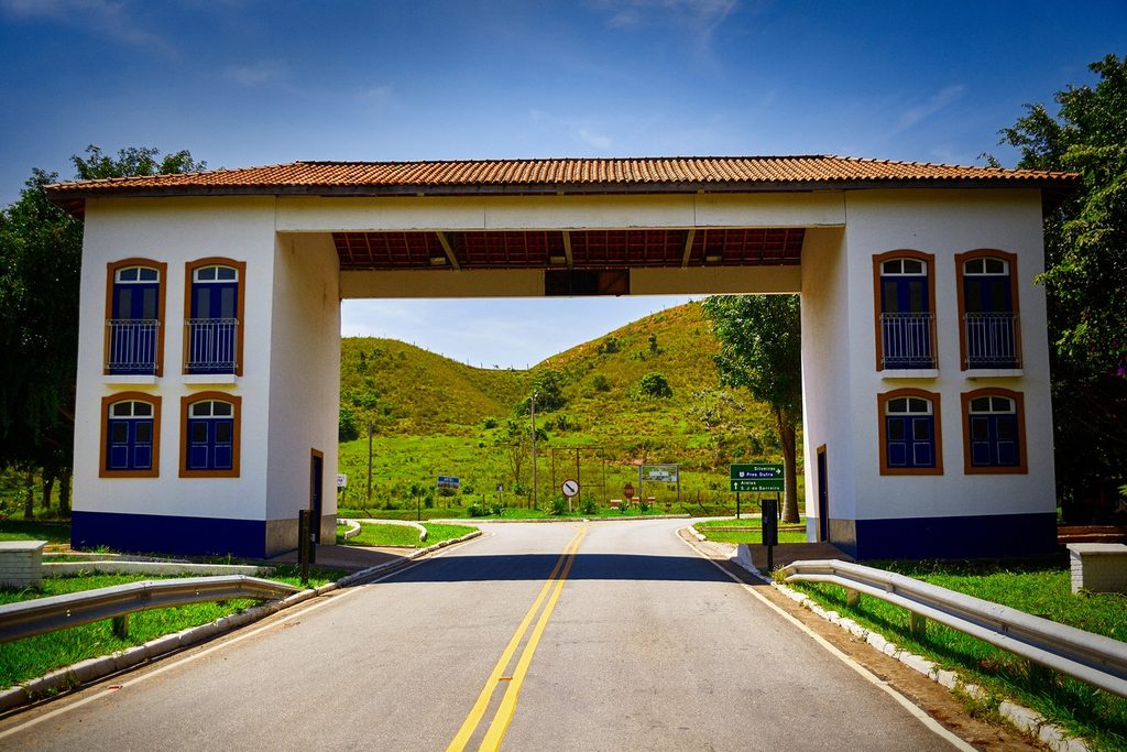 Portal de entrada de Areias, construção branca em estilo colonial sobre a estrada, com morros verdes ao fundo
