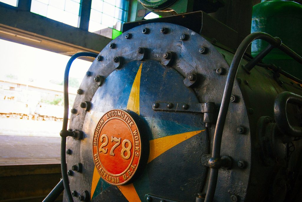 Detalhe da frente de uma locomotiva a vapor com estrela amarela e placa redonda com o número 278