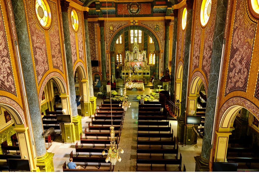 Interior da Igreja de São João Batista, com colunas e paredes decoradas em dourado e vermelho e o altar ao fundo