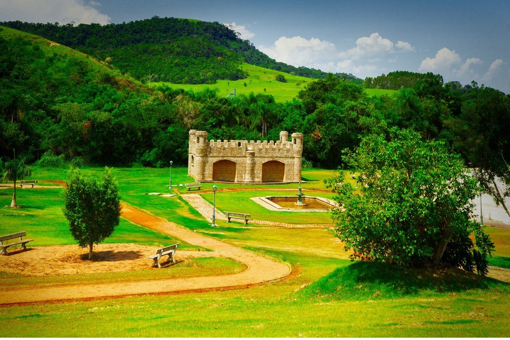 Construção em forma de castelo com ameias no Espaço Castelo, em Bofete, cercada de gramado e morros verdes