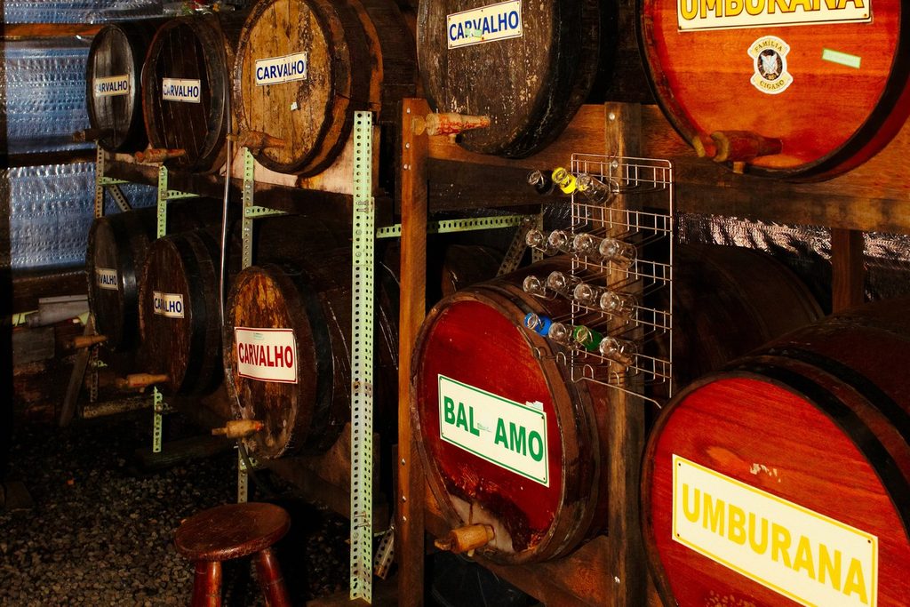 Barris de madeira de cachaça empilhados em prateleiras no alambique Zé da Vargem