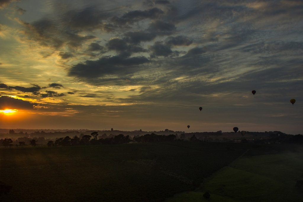 Nascer do sol visto de dentro de um balão, com outros balões ao longe sobre os campos de Boituva