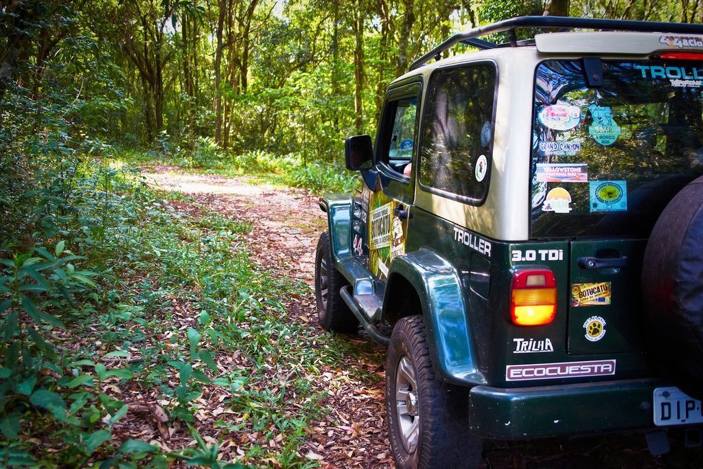Jipe 4x4 verde parado numa trilha de terra no meio da mata da Cuesta