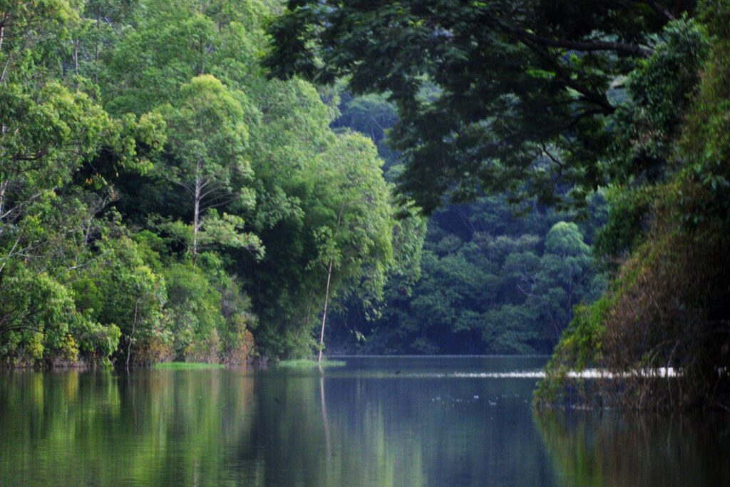 Represa do Rio Jaguari, em Bragança Paulista, com água calma refletindo a mata densa das margens