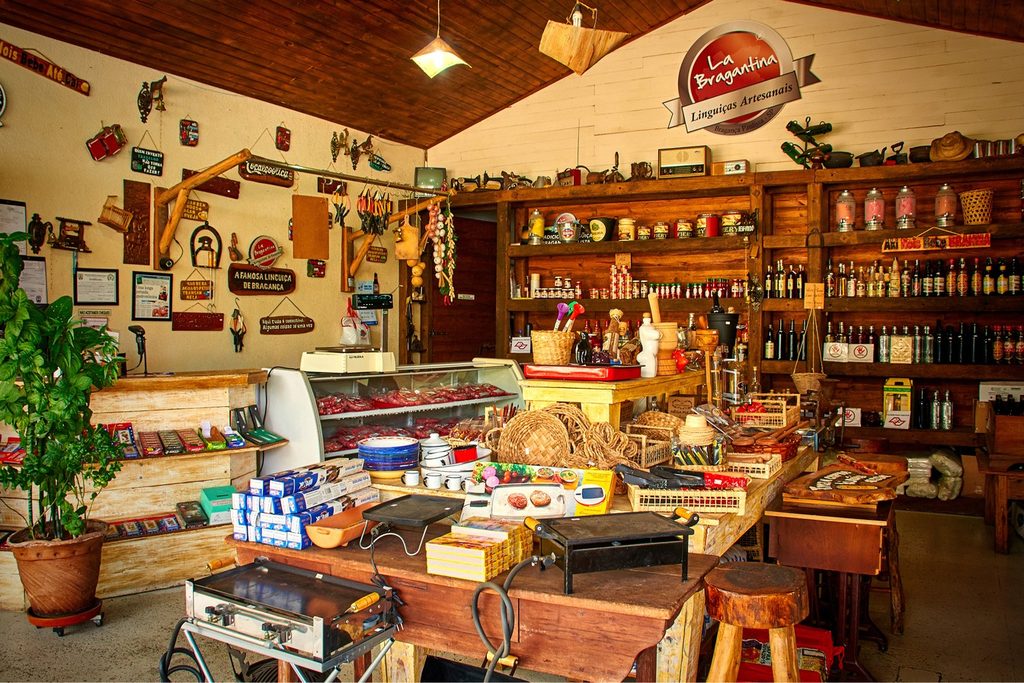 Empório de linguiça artesanal em Bragança Paulista, com balcão refrigerado, prateleiras de madeira cheias de produtos e decoração rústica