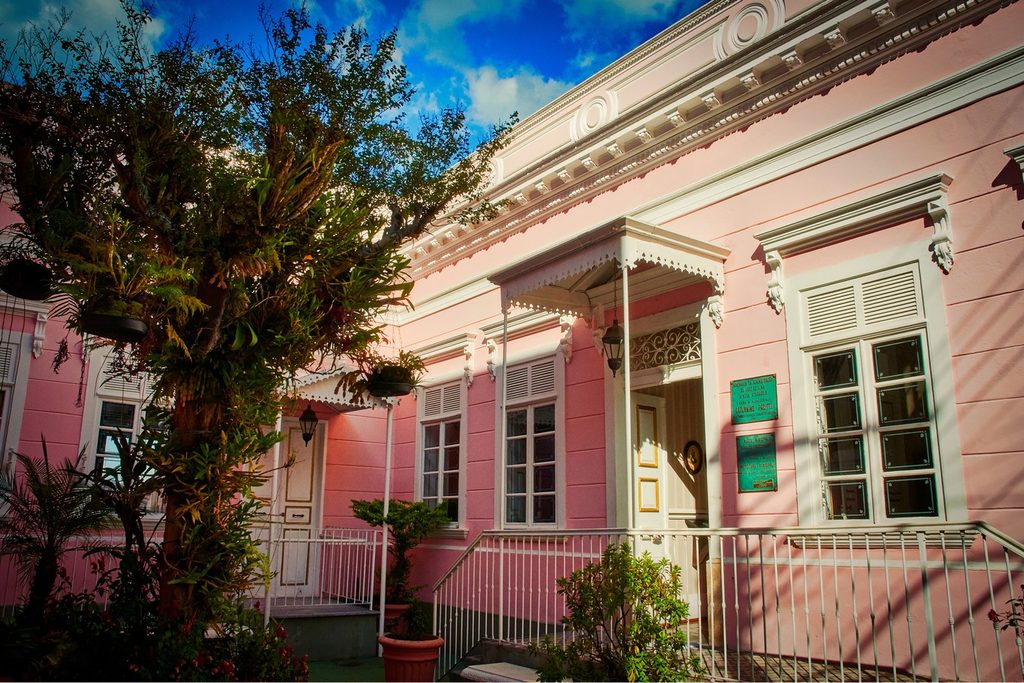 Casarão rosa de 1896 com janelas brancas, varandinha de ferro e plantas, sede do Museu Municipal Oswaldo Russomano