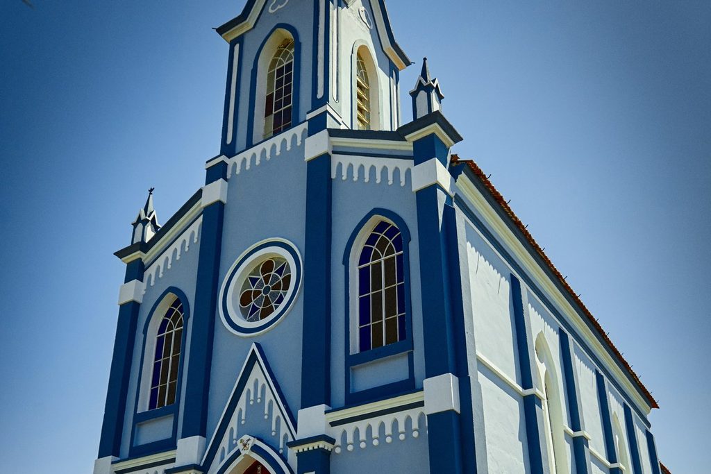 Igreja do Bom Jesus, azul e branca, com torre pontuda e porta vermelha