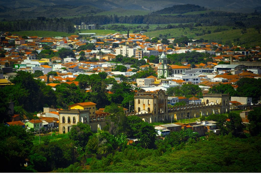Vista do alto de Cachoeira Paulista, com telhados, a igreja e o prédio comprido da estação ferroviária