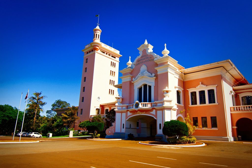 Prédio rosa em estilo neocolonial da Escola Preparatória de Cadetes do Exército, com torre branca alta e fachada ornamentada