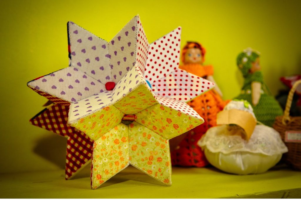 Estrela de tecido estampado e bonecas de pano feitas à mão, sobre um fundo amarelo