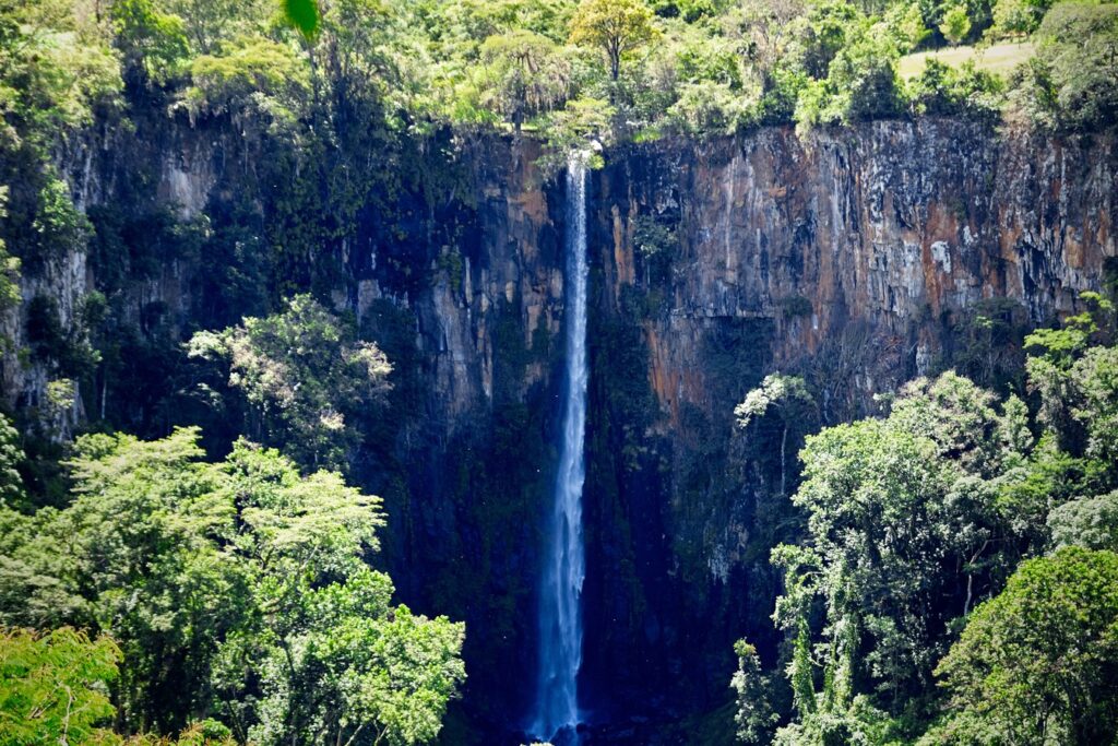 Cachoeira do Itambé, em Cássia dos Coqueiros, caindo fina e alta de um paredão de pedra escura cercado de mata