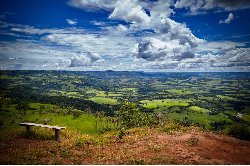 Banco de madeira no alto do Mirante das Areias, em Cássia dos Coqueiros, com vista para um vale de pastos e morros até o horizonte