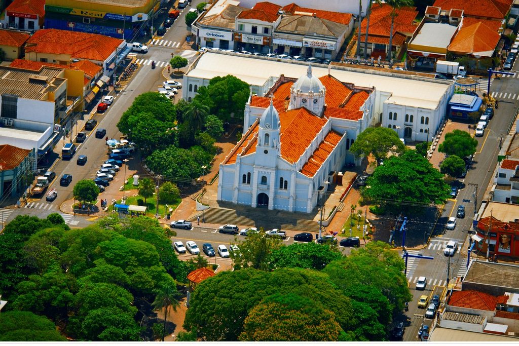Vista aérea da Igreja Matriz do Senhor Bom Jesus, branca, cercada de árvores e ruas do centro