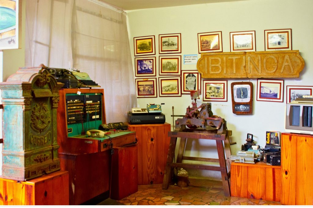 Sala do museu com quadros antigos na parede, móveis de madeira e uma placa entalhada com o nome Ibitinga