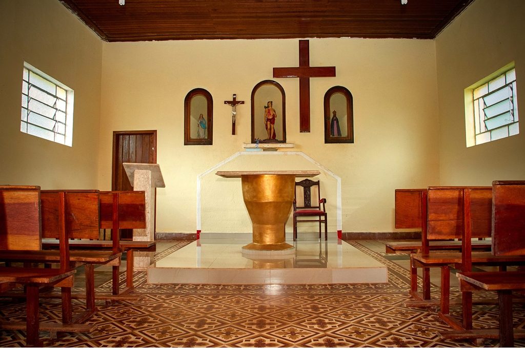 Interior da capela do Santuário de São Sebastião, com bancos de madeira, altar claro e cruz na parede