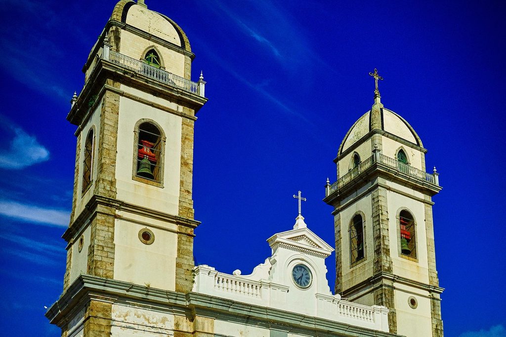 Torres brancas da Basílica do Senhor Bom Jesus com relógio no frontão, sob céu azul