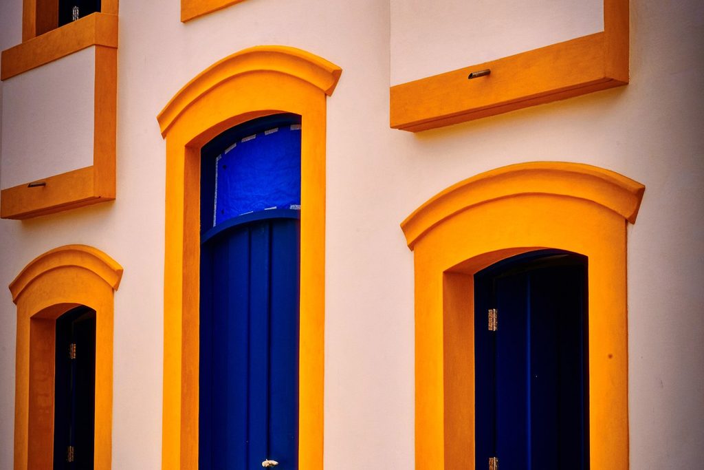 Fachada branca do Museu Histórico e Arqueológico de Iguape, antiga Casa de Fundição, com portas azuis e molduras amarelas