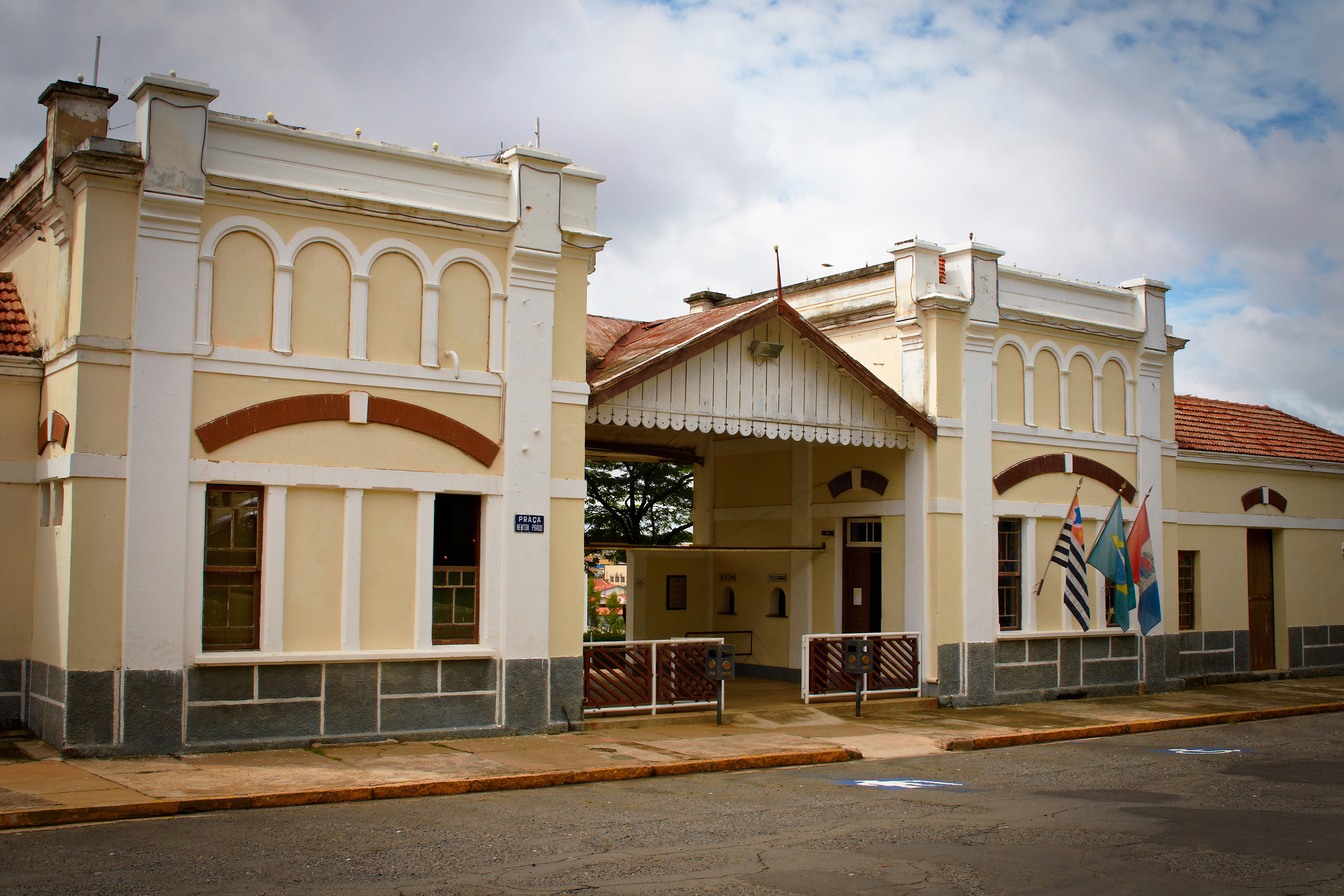 Fachada creme da antiga estação ferroviária de Indaiatuba, hoje Museu Ferroviário, com janelas em arco e bandeiras na entrada