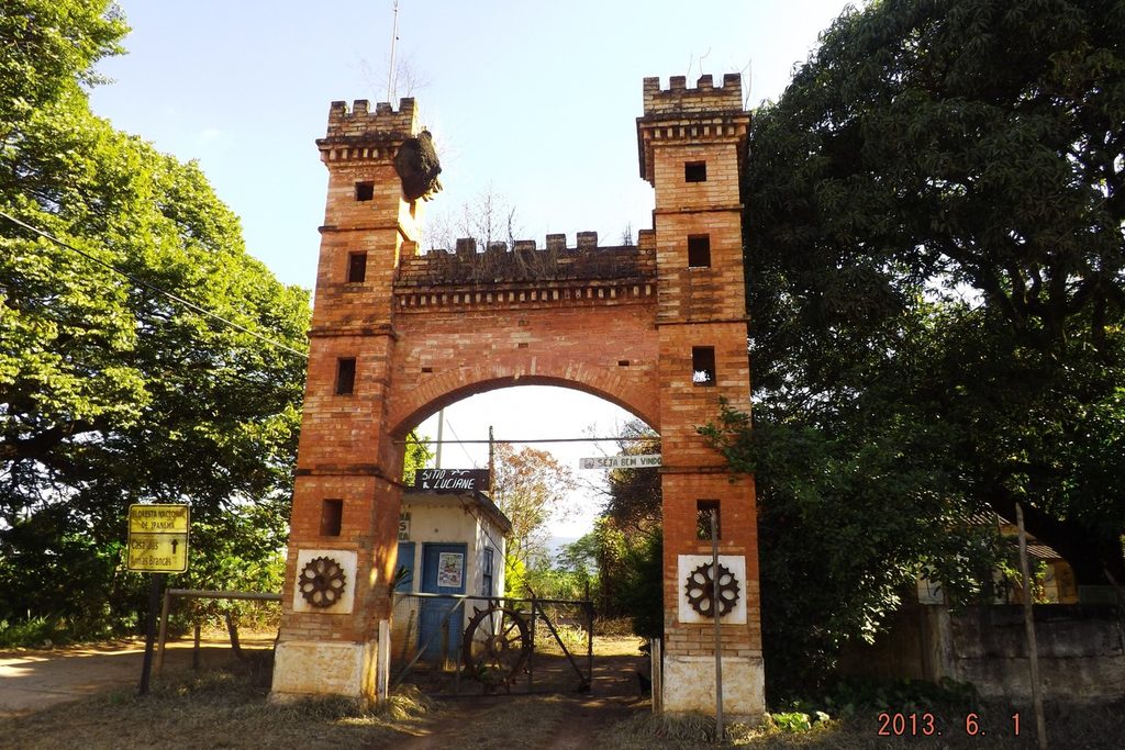 Portal de entrada de tijolos com duas torres e ameias, como um castelo, entre árvores, na entrada da Fazenda Ipanema
