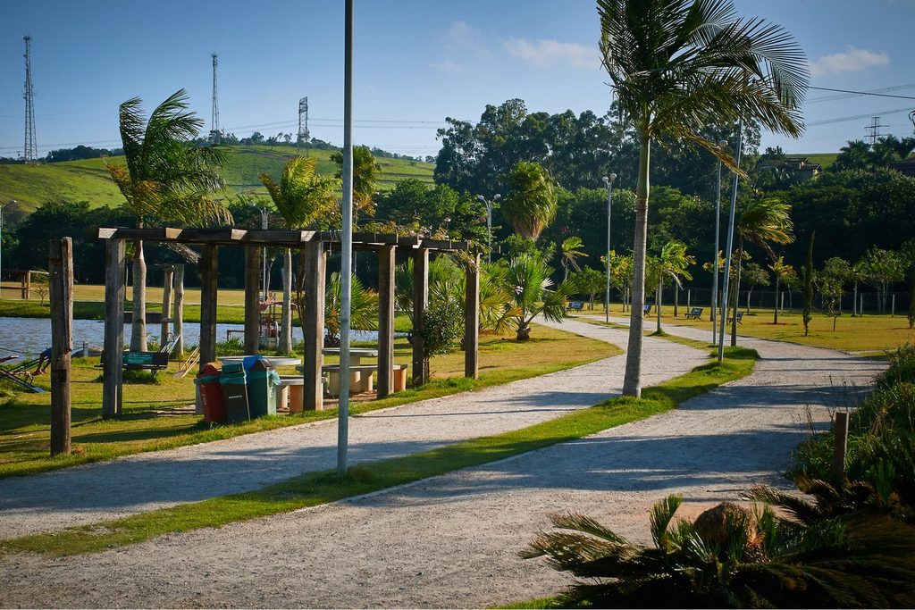 Pista de caminhada entre palmeiras e gramado no Parque Luis Latorre, em Itatiba, com o lago à esquerda