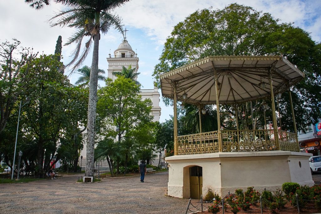 Coreto de ferro da Praça da Bandeira, em Itatiba, com a torre branca da Basílica de Nossa Senhora do Belém ao fundo
