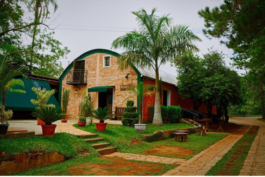 Prédio de tijolos aparentes da Rofer Cervejaria Artesanal, com jardim e palmeiras, em Itupeva