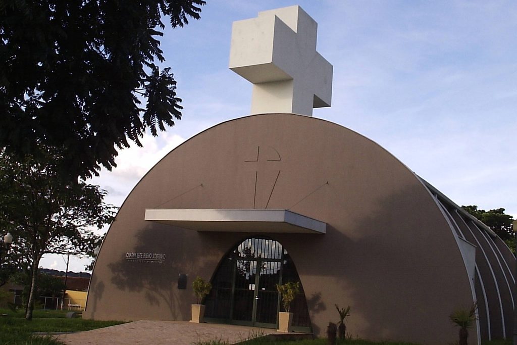 Prédio em forma de arco com uma grande cruz branca no alto, onde funciona a Pinacoteca de Jaboticabal