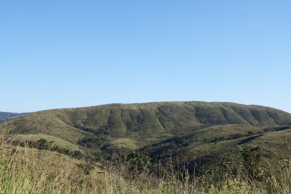 Morro arredondado coberto de vegetação baixa sob céu azul, o Ovo da Pata