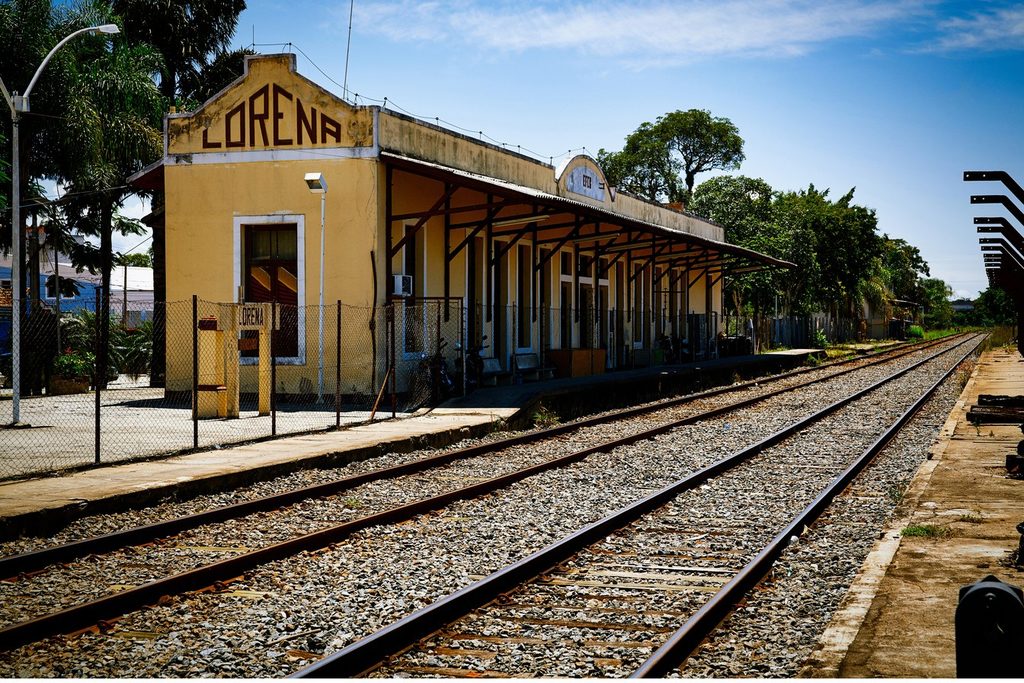 Estação ferroviária amarela com o nome Lorena no alto e trilhos em primeiro plano