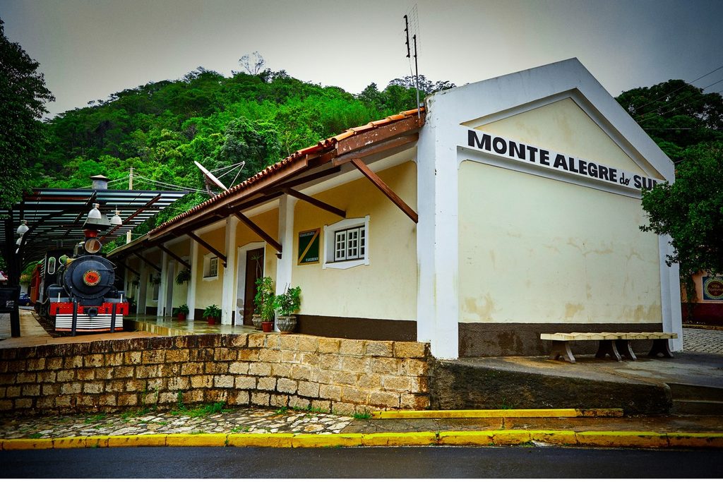 Antiga estação ferroviária de Monte Alegre do Sul, com o nome da cidade na fachada e uma locomotiva preta exposta na plataforma