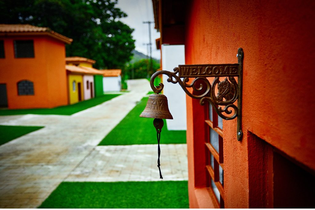 Casinhas coloridas em miniatura com sino de ferro e placa de boas-vindas na Mini Cidade de Monte Alegre do Sul