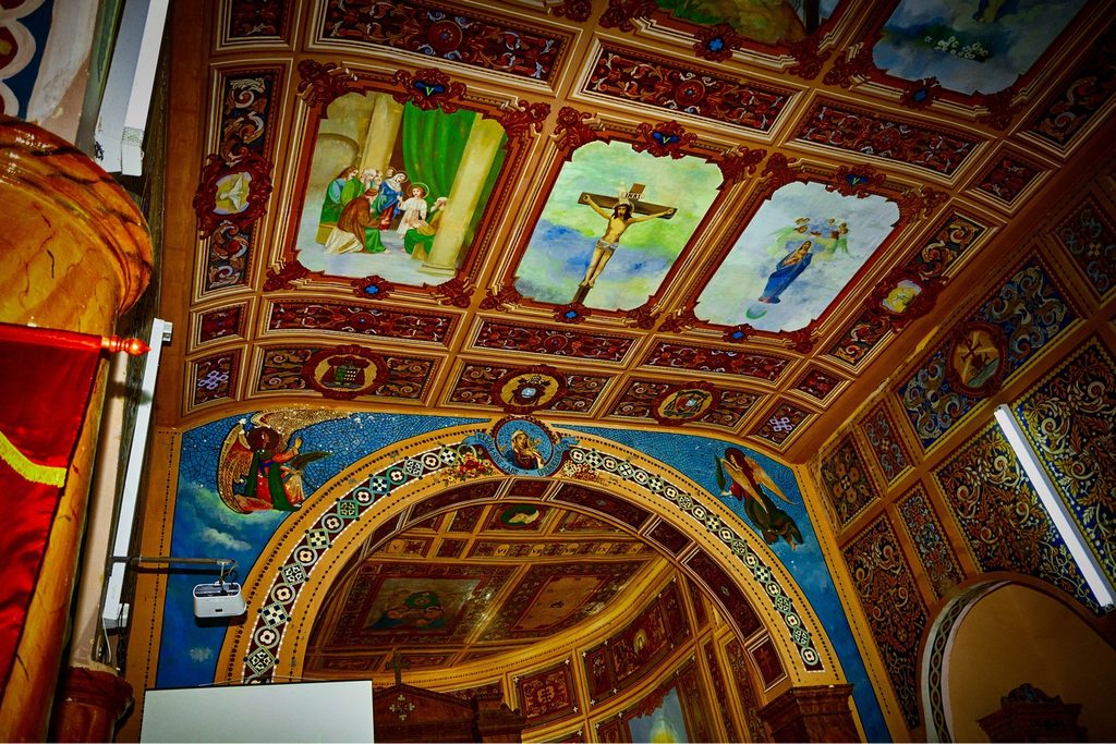 Teto da igreja todo pintado com imagens de santos, arcos decorados e cores fortes, na Matriz de Monteiro Lobato