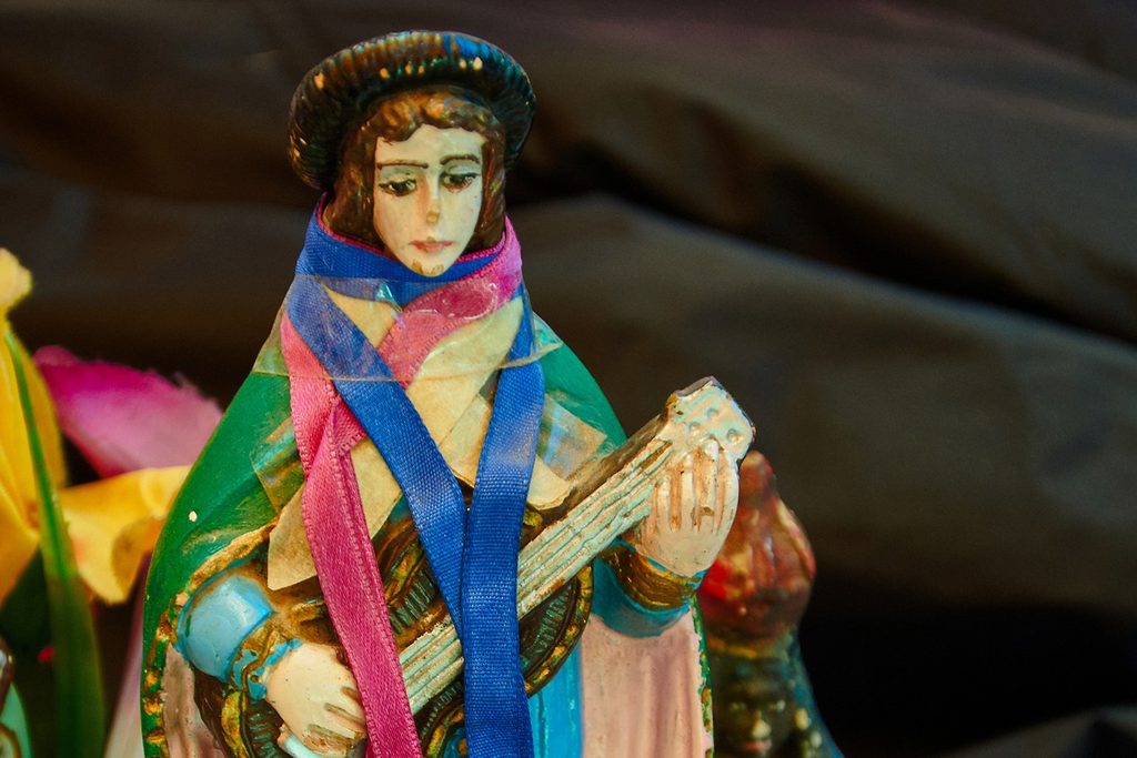Imagem colorida de São Gonçalo com viola e fitas, enfeitada para a festa