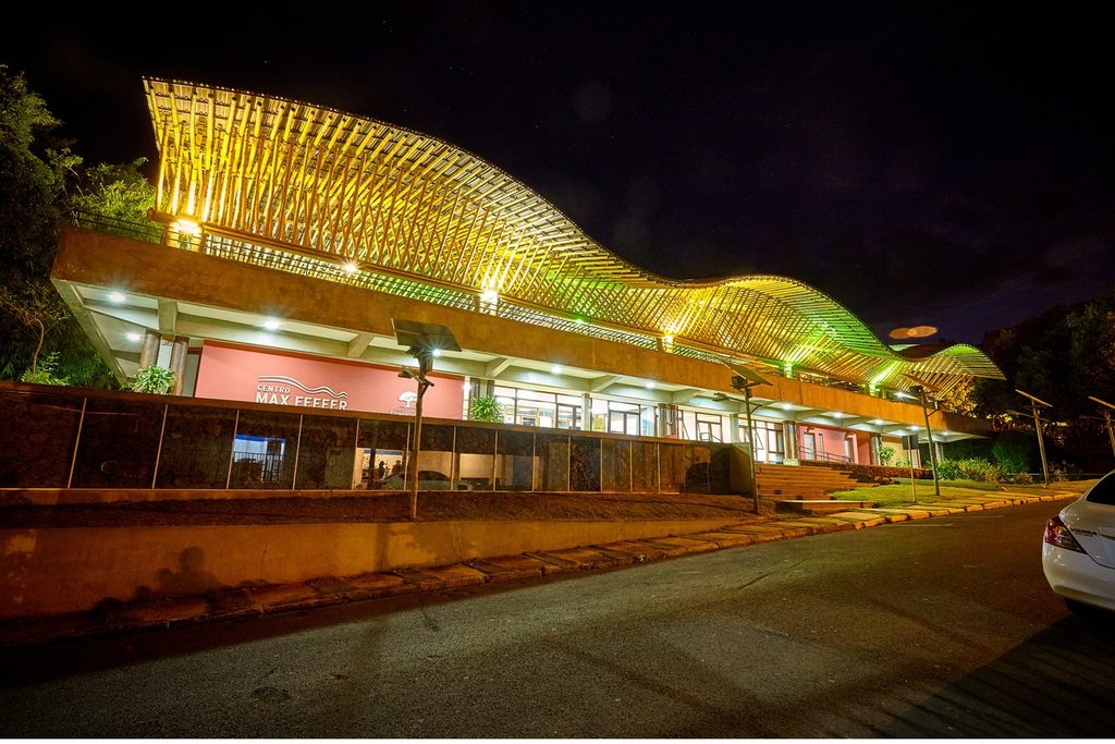 Centro Max Feffer de Cultura e Sustentabilidade iluminado à noite, com cobertura ondulada