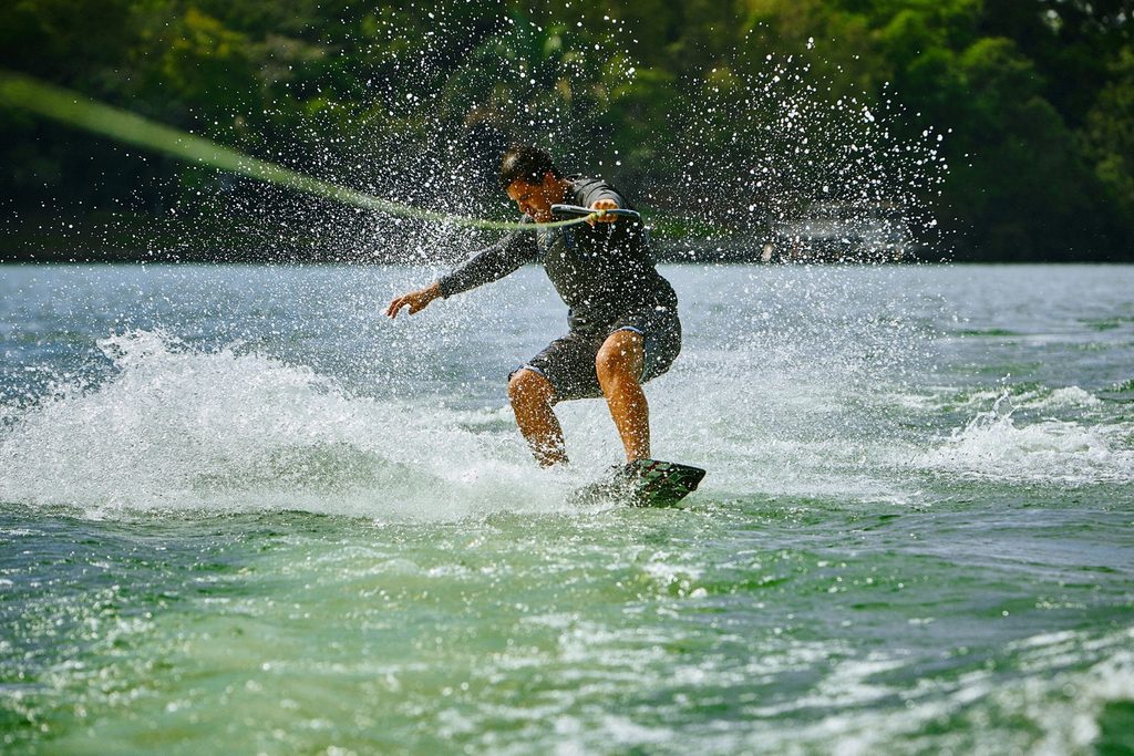 Homem fazendo wakeboard no lago de Pedregulho, levantando água com a prancha
