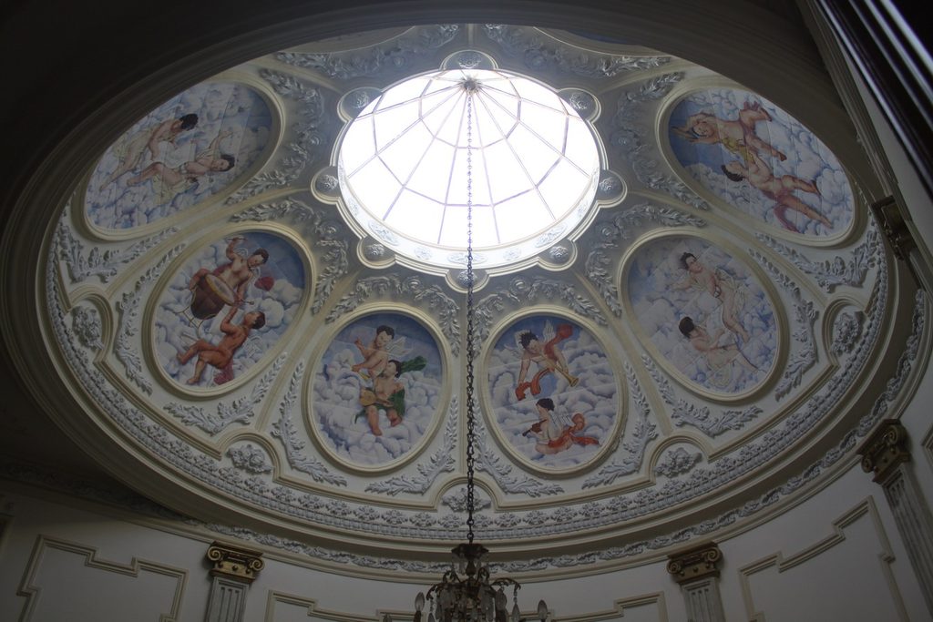 Cúpula do museu vista de baixo, com claraboia de vidro no centro e anjos pintados em medalhões